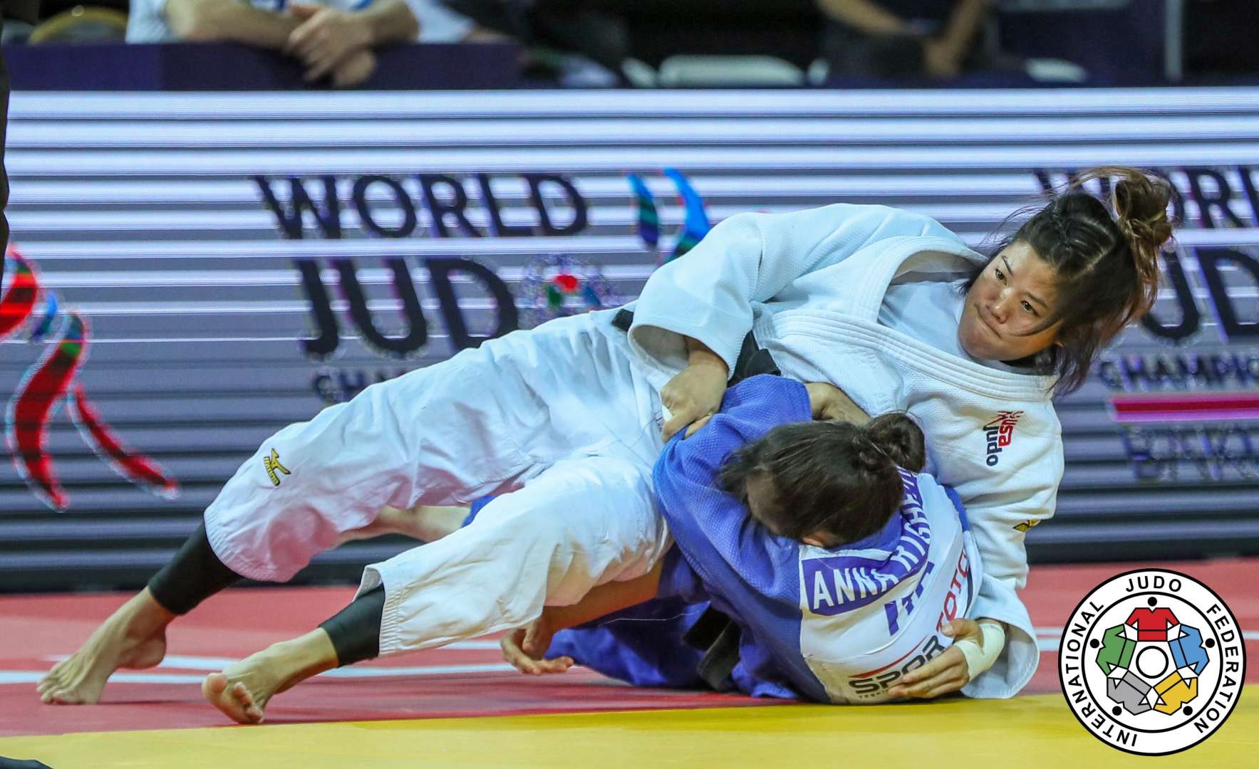 A judoka tying a black belt over a white judogi
